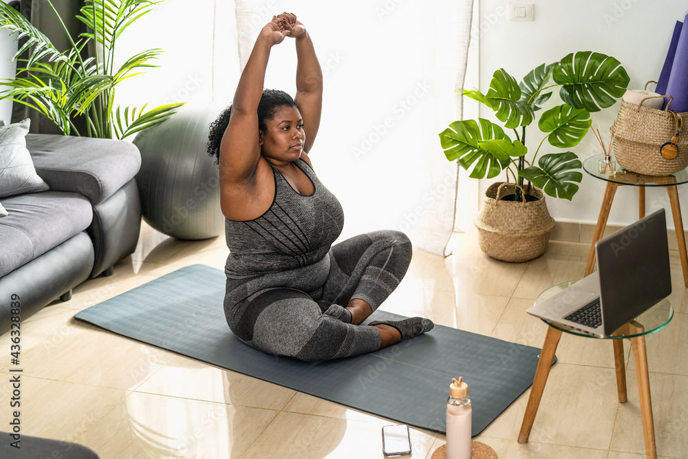 Woman exercising on mat in front of PC 