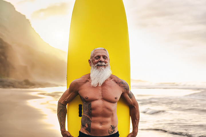 fit elderly man holding surfboard