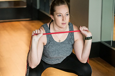 Woman exercising with band in squat position 